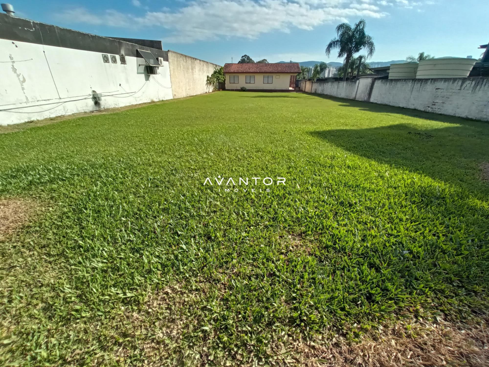 Terreno com área verde e construções ao fundo — Terreno para alugar em Nossa Senhora de Lourdes, Santa Maria/RS