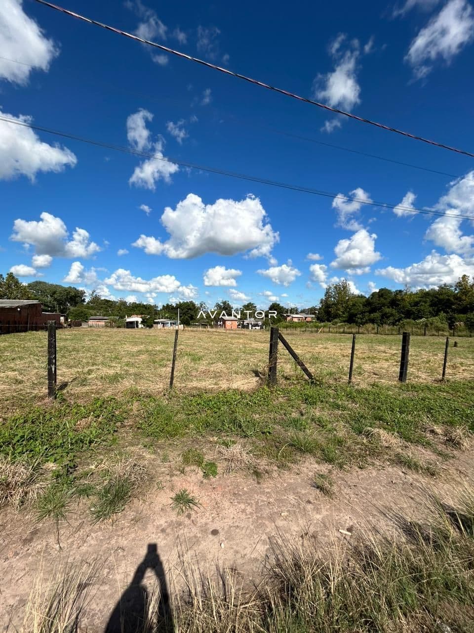 Terreno com cerca e construções ao fundo — Terreno à venda em Diácono João Luiz Pozzobon, Santa Maria/RS