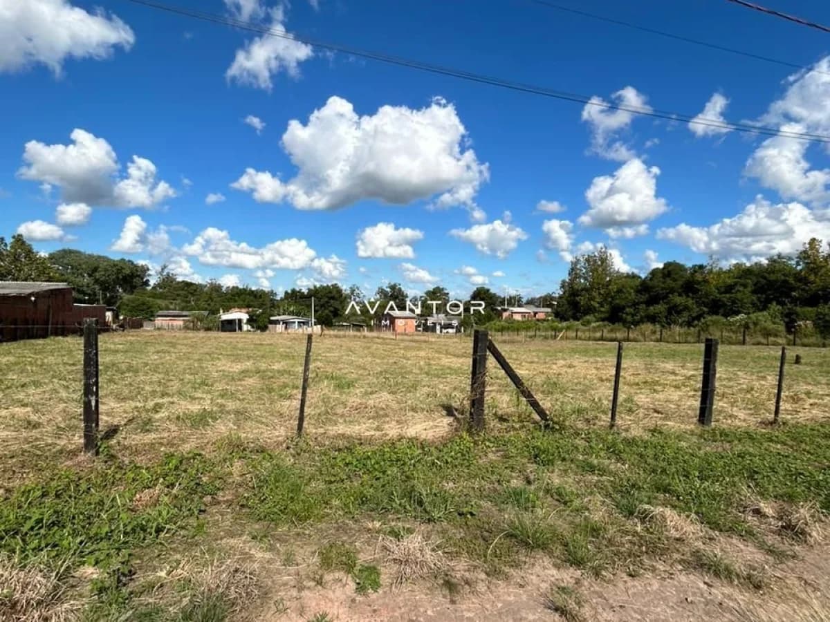 Terreno com cerca e construções ao fundo — Terreno à venda em Diácono João Luiz Pozzobon, Santa Maria/RS