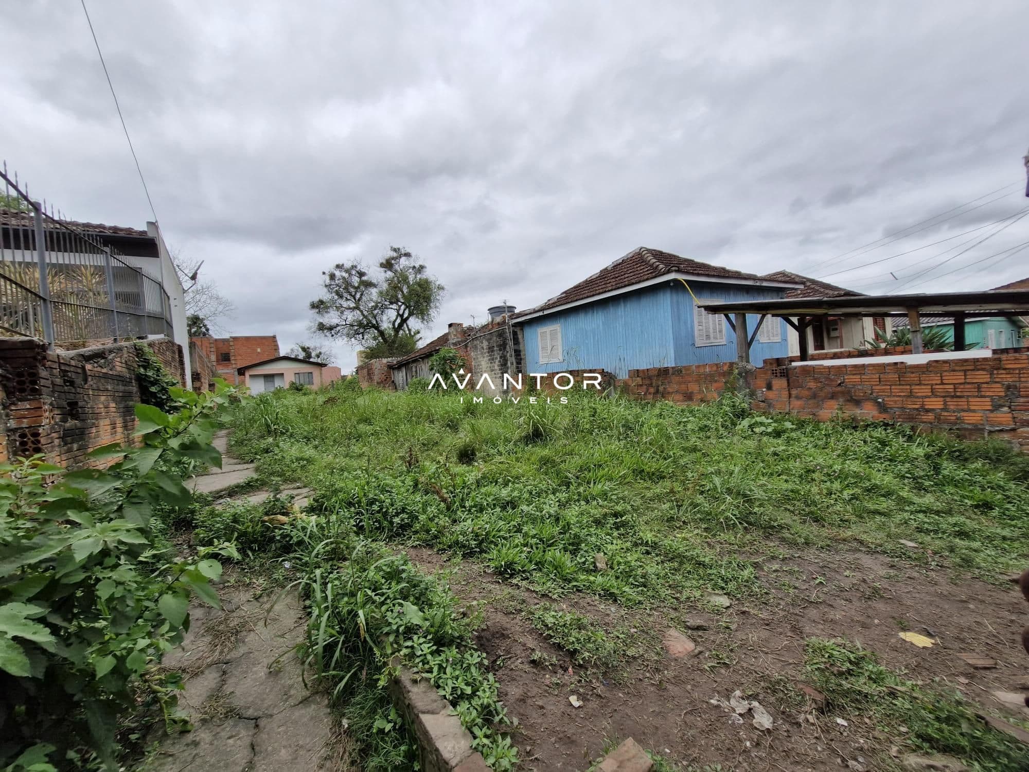 Terreno com vegetação e casarões ao fundo — Terreno à venda em Nossa Senhora do Perpétuo Socorro, Santa Maria/RS