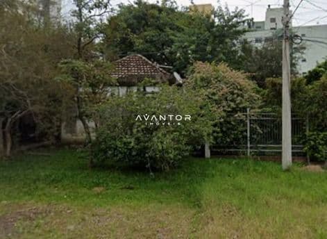 Terreno com vegetação e construção ao fundo — Terreno à venda em Menino Jesus, Santa Maria/RS