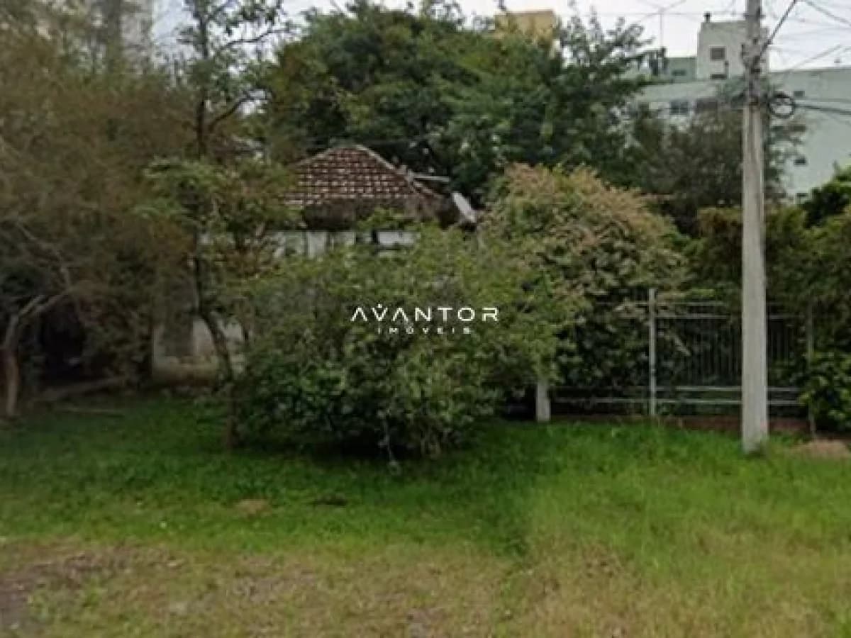 Terreno com vegetação e construção ao fundo — Terreno à venda em Menino Jesus, Santa Maria/RS