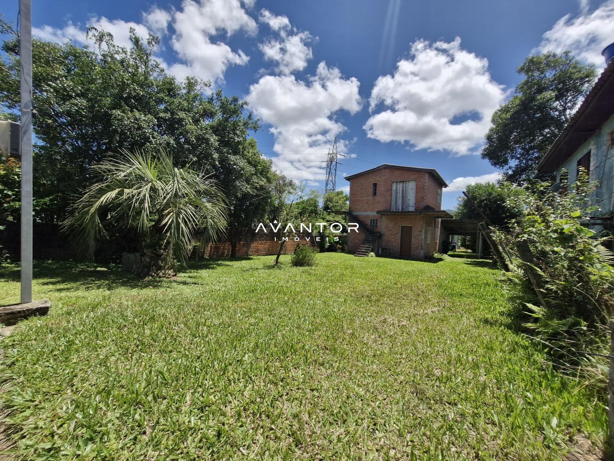 Fachada da casa com pátio e vegetação — Terreno à venda em Itararé, Santa Maria/RS
