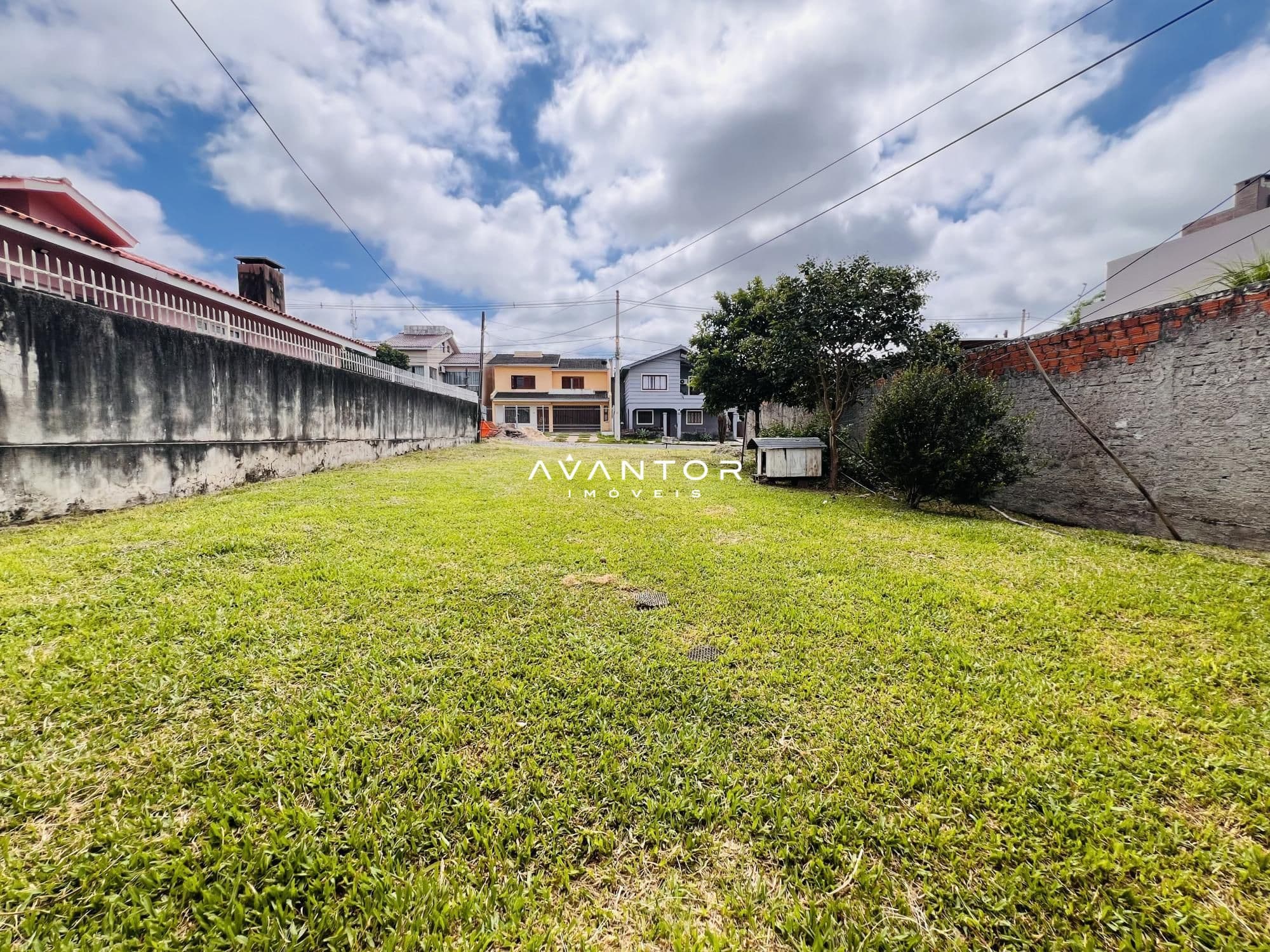 Terreno com grama e casarões ao fundo — Terreno à venda em Camobi, Santa Maria/RS