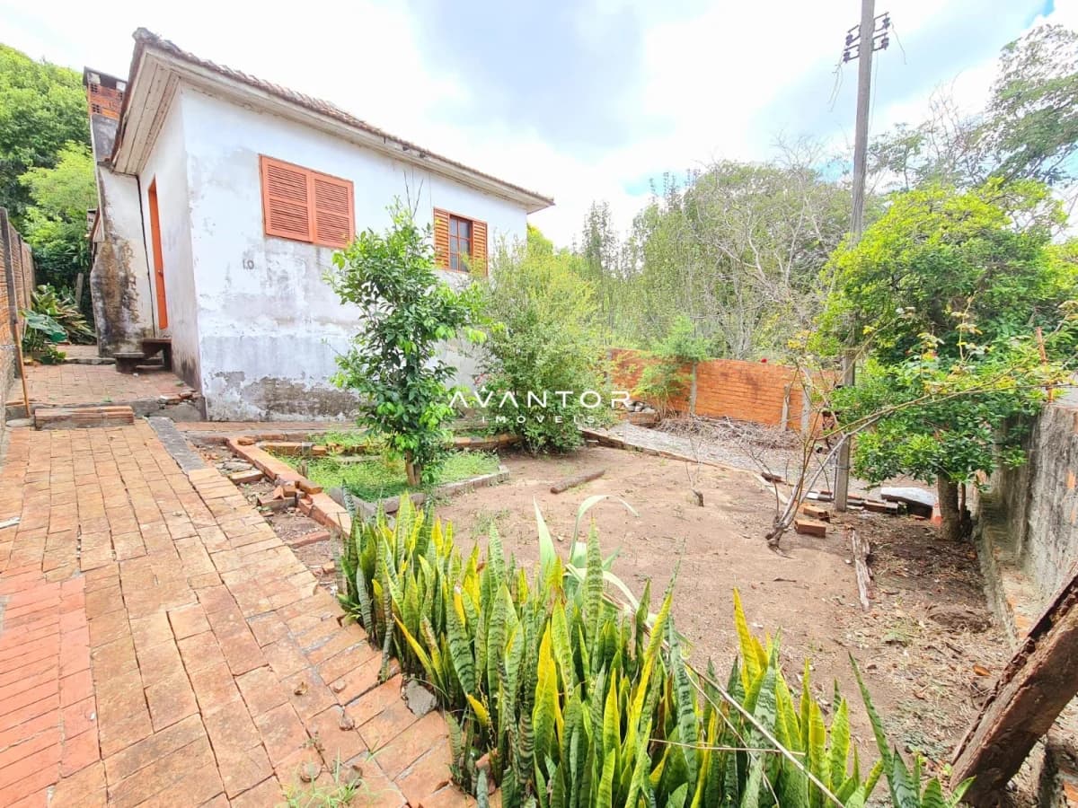 Fachada da casa com pátio e plantação — Terreno à venda em Nossa Senhora de Lourdes, Santa Maria/RS