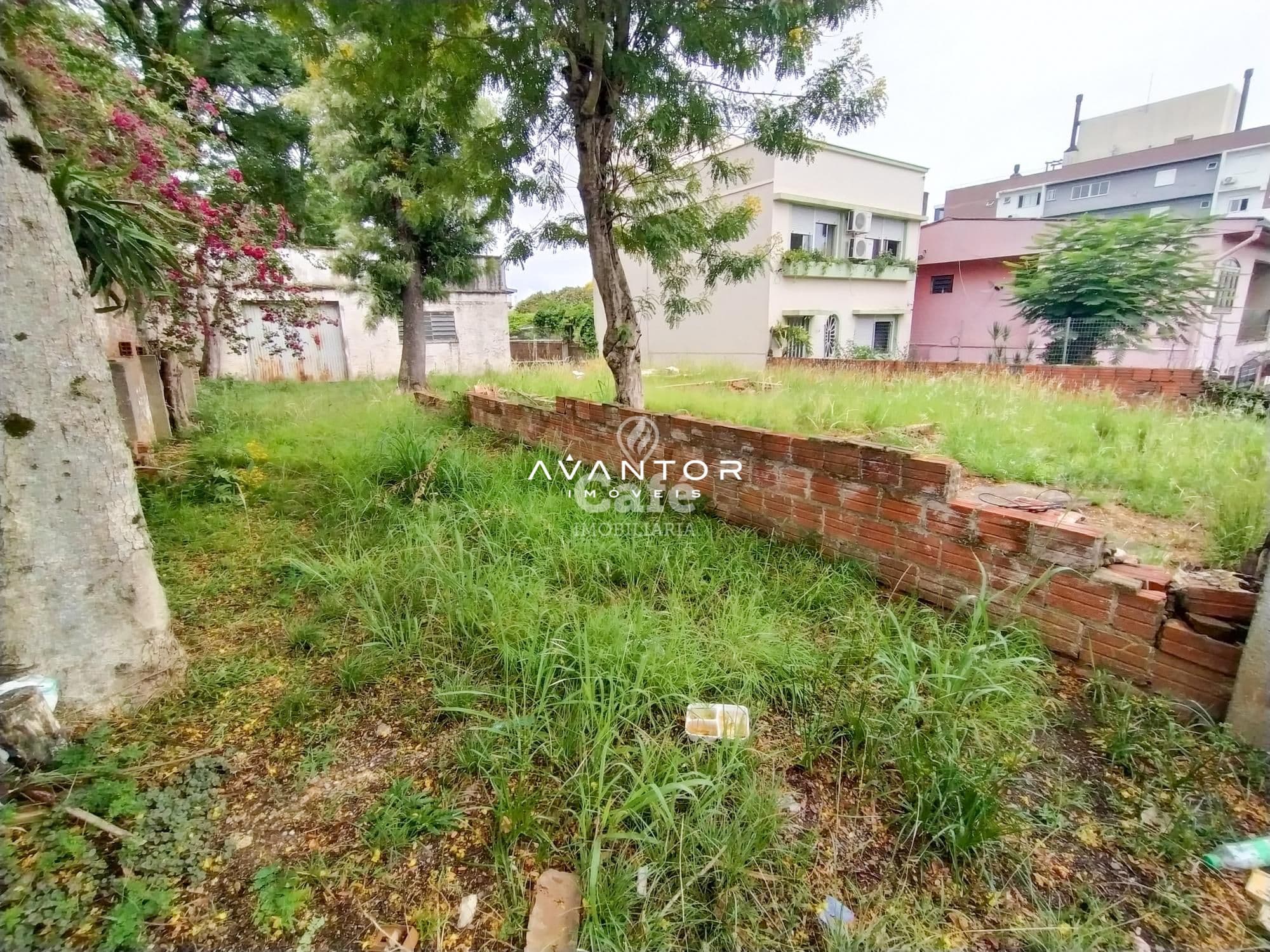 Terreno com vegetação e casarões ao fundo — Terreno à venda em Nossa Senhora de Lourdes, Santa Maria/RS