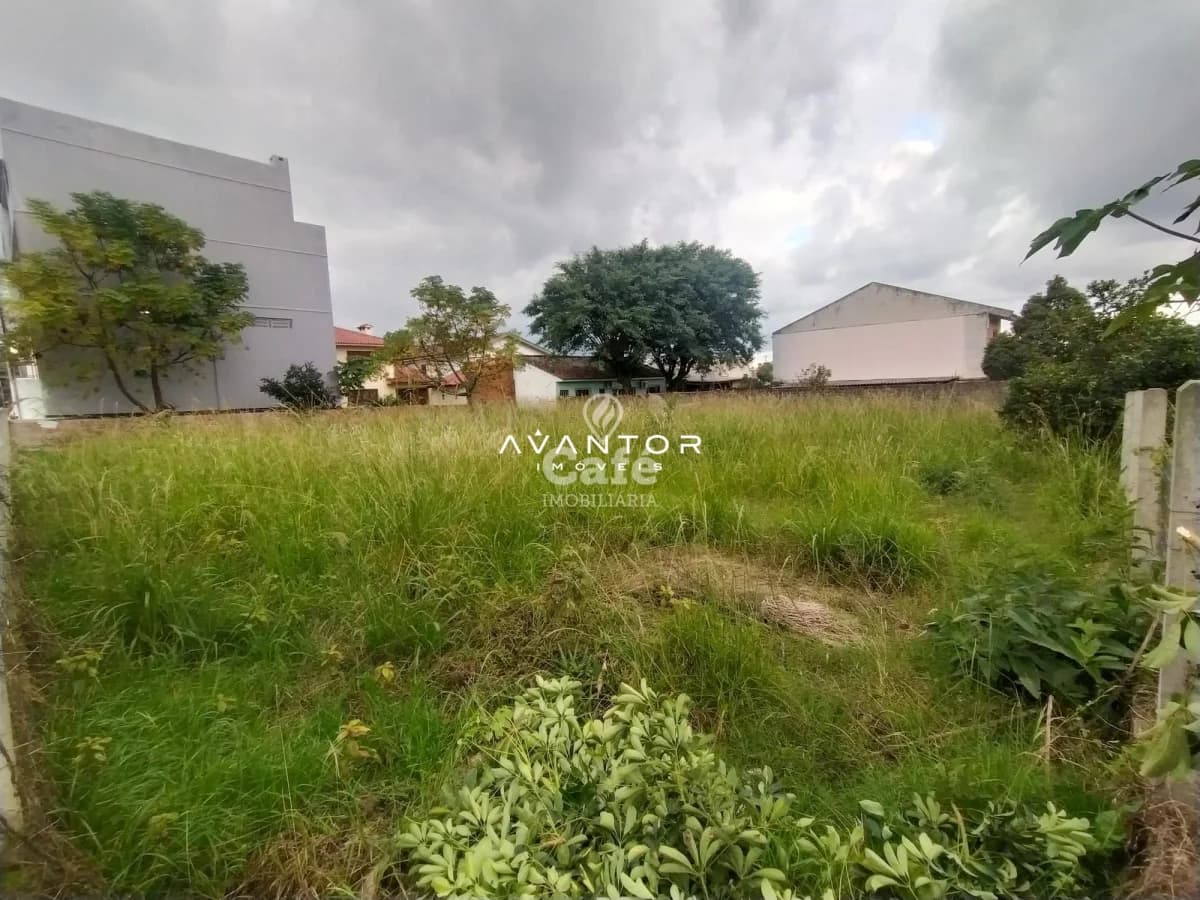 Terreno com vegetação e edificações ao fundo — Terreno à venda em Dom Antônio Reis, Santa Maria/RS